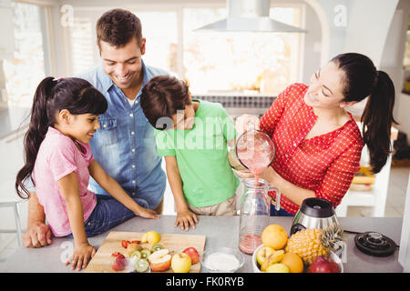 Famille heureuse avec la mère de verser le jus de fruit en jug Banque D'Images