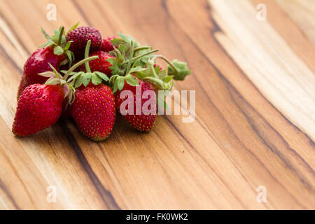 Close up d'un tas de fraises sauvages rouge fraîchement cueillies sur une table en bois Banque D'Images