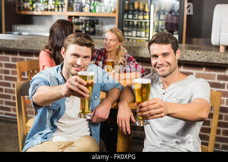 Men toasting en face tandis que les femmes parlent derrière Banque D'Images
