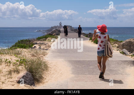 Une femelle en tourisme une pastèque pastèque et haut chapeau de couleur le long de la chaussée de marche à Nobby's Head, Newcastle Banque D'Images