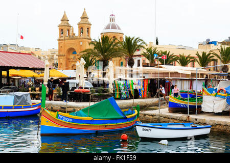 Luzzu maltais traditionnels bateaux de pêche dans le port de Marsaxlokk avec l'église de Notre-Dame de Pompéi derrière, Marsaxlokk, Malte. Banque D'Images