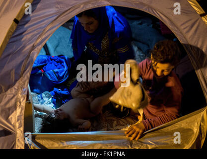 Idomeni, Grèce. Le 05 Mar, 2015. Un enfant réfugié est diapered par sa mère et sa soeur dans leur tente dans le camp de réfugiés de l'Greek-Macedonian Idomeni à la frontière, de la Grèce, 05 mars 2015. Seul un petit nombre de réfugiés en provenance de Syrie et l'Irak sont encore en Macédoine chaque jour. Photo : KAY NIETFELD/dpa/Alamy Live News Banque D'Images