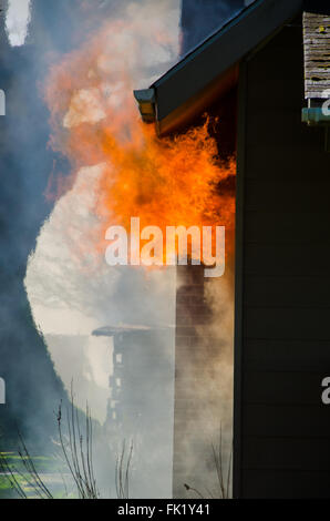 Lèche flambante de par la fenêtre d'une maison entourée d'une épaisse fumée noire Banque D'Images