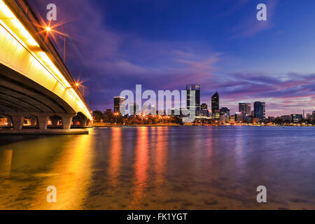 Colorful le lever du soleil sur la ville de Perth CBD sur la connexion de pont sur la rivière Swan. Les lumières vives reflétant dans l'eau toujours propre Banque D'Images