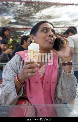 Indian woman holding an ice cream cone et talking on mobile phone. Banque D'Images