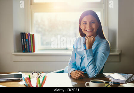 Confident business woman sitting at desk in office smiling at the camera portant un t-shirt bleu Banque D'Images