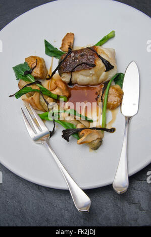 Cabillaud rôti, confit d'ailes de poulet, jus de poulet salsifis et woodruff.Un UK Food plate plat de restaurants servant une cuisine de plats plaques Banque D'Images