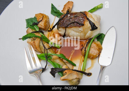 Cabillaud rôti, confit d'ailes de poulet, jus de poulet salsifis et woodruff.Un UK Food plate plat de restaurants servant une cuisine de plats plaques Banque D'Images