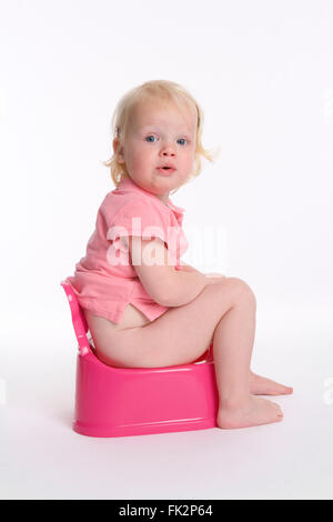 Bébé fille est assise sur un pot pour la formation de pot sur fond blanc Banque D'Images