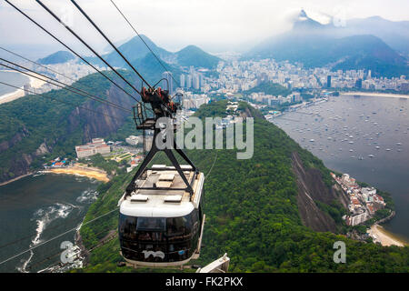Un câble panier descendre Pain de Sucre (Pão de Açúcar) à Rio de Janeiro, Brésil avec le Christ Rédempteur stature devant Banque D'Images