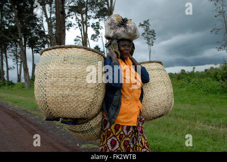 Une femme congolaise équilibrant une charge sur sa tête alors qu'elle transporte de grands sacs de paille tissée dans une zone rurale de la province du Nord-Kivu en République démocratique du Congo en Afrique Banque D'Images