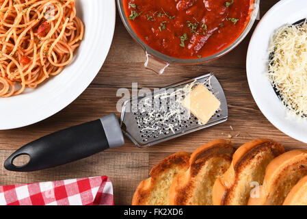 Portrait d'un Italien repas sur une table de cuisine en bois rustique. Une assiette de spaghetti, bol de sauce, parmesan râpé, Banque D'Images
