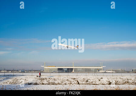 Poussette avec chien le long de la clôture de sécurité à l'avant d'un avion décollant de la piste du sud de l'aéroport de Munich sur un jour d'hiver Banque D'Images