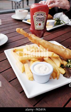 Assiette de poisson traditionnelle britannique et puces avec petits pois et bouteille de ketchup Heinz Banque D'Images