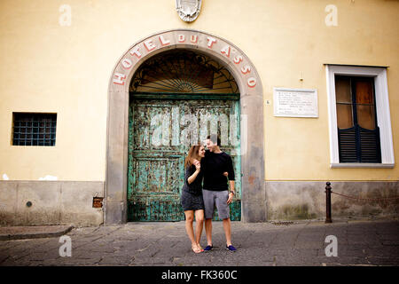 Un jeune couple dans l'amour brunette en face d'un merveilleux, vieux bâtiment italien, méditerranéen, grand portail vert archway Banque D'Images