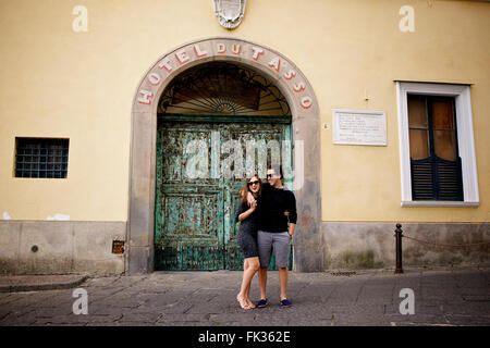 Un jeune couple dans l'amour brunette en face d'un merveilleux, vieux bâtiment italien, méditerranéen, grand portail vert archway Banque D'Images