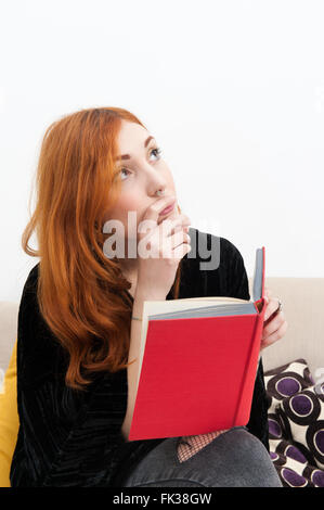 Jeune rousse femme lisant un livre avec couvercle vide rouge jusqu'à la Banque D'Images