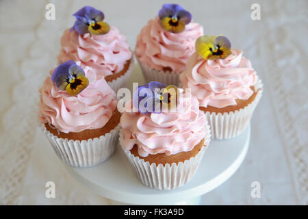 Glaçage rose maison cupcakes vanille avec fleurs comestibles Banque D'Images