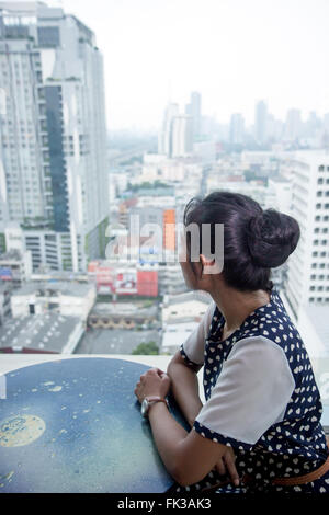 Jeune femme assise à une table près de la fenêtre dans un gratte-ciel Banque D'Images