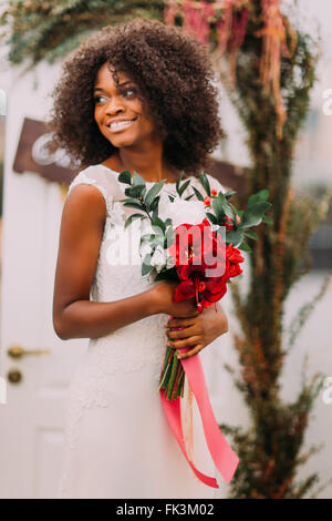 Magnifique africaine moony libres avec bouquet de fleurs rouges sur la cérémonie de mariage Banque D'Images