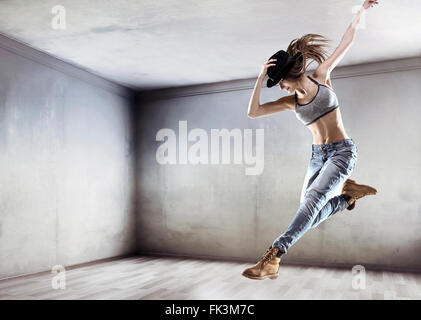 Jeune danseur athlétique de sauter sur un mur de béton background Banque D'Images