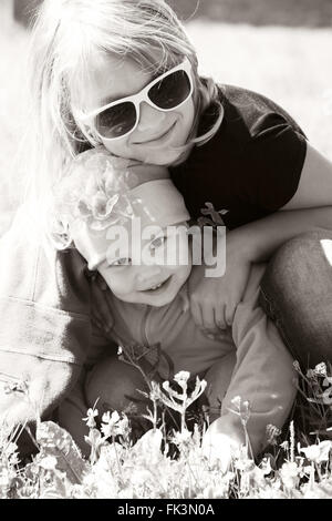 Petite blonde Young sisters hugging dans une journée ensoleillée. Closeup portrait monochrome sépia Banque D'Images