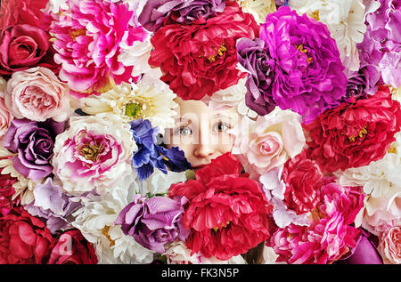 Image conceptuelle de petite fille derrière un mur de fleurs Banque D'Images