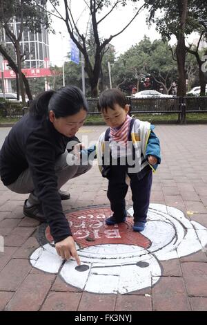 Chengdu, province chinoise du Sichuan. 7 mars, 2016. Un enfant regarde son couvercle peint avec une caricature de droit dans le sud-ouest de Chengdu, capitale de la province chinoise du Sichuan, le 7 mars 2016. Credit : Liu Kun/Xinhua/Alamy Live News Banque D'Images