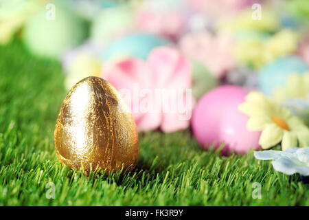 Les oeufs de Pâques colorés sur l'herbe avec des oeufs d'or Banque D'Images