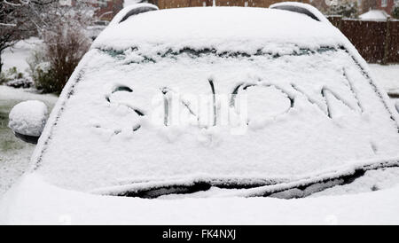 Voiture avec le mot 'snow' écrit dans le pare-brise couvert de neige Banque D'Images