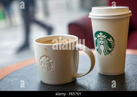 Café Starbucks tasses sur une table et la rue devant la fenêtre Banque D'Images