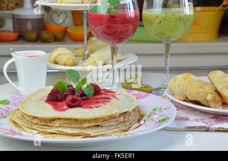 Les crêpes avec de la gelée de framboise naturelle et la mélisse avec kiwi et framboises fraîches smoothies servis pour le petit-déjeuner Banque D'Images