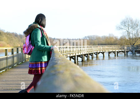 Jeune femme regarde l'autre côté de la rivière de pont en bois. Banque D'Images