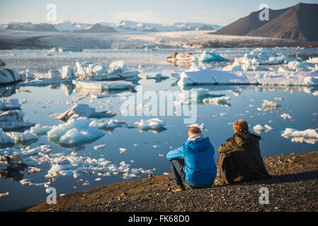 Père et fils en vacances au bord de la Lagune glaciaire du Jökulsárlón au coucher du soleil, au Sud Est de l'Islande, Islande, régions polaires Banque D'Images