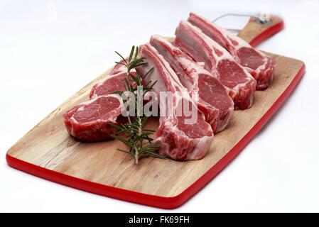 Matières des côtelettes d'agneau au romarin sur planche à hacher fond blanc Banque D'Images