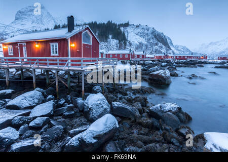 Maisons de pêcheurs typiques appelés rorbu dans le paysage de neige au crépuscule, Nusfjord, comté de Nordland, îles Lofoten, Norvège Banque D'Images