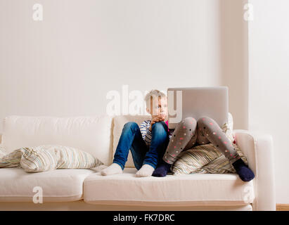 Enfants à la maison assis sur un canapé, jouer avec coffre Banque D'Images