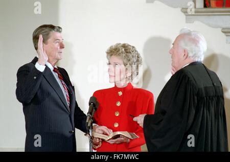 Le président américain Ronald Reagan d'être assermenté pour deuxième mandat par le juge en chef Warren Burger en tant que première dame Nancy Reagan regarde pendant la cérémonie privée à la Maison Blanche le 20 janvier 1985 à Washington, DC. Banque D'Images