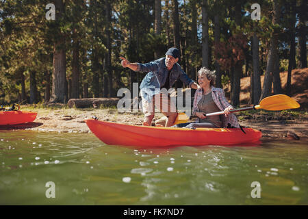 Portrait d'homme mûr avec une femme dans un kayak dans le lac. homme montrant quelque chose d'intéressant à woman holding pagaies. C Senior Banque D'Images