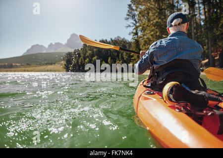 Vue arrière droit d'un homme canoë dans un lac. Une balade en kayak sur l'homme journée d'été. Banque D'Images