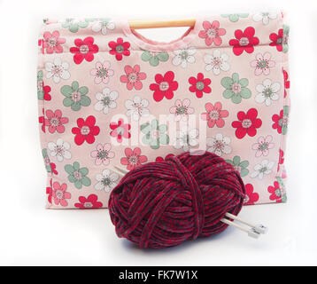 Tricot à motifs fleurs rose / artisanat sac avec des aiguilles à tricoter, laine et bourgogne isolé sur un fond blanc. Banque D'Images