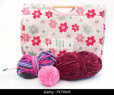 Tricot à motifs fleurs rose / artisanat sac avec des aiguilles à tricoter, et rose, rouge et la laine multicolore sur un fond blanc. Banque D'Images