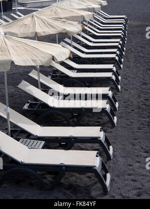 Chaises longues blanc vide sur le sable de lave volcanique noire, début de matinée à Alcala Tenerife Espagne Banque D'Images