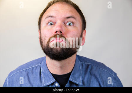 L'homme à son milieu-30's pose pour un portrait de studio avec un semi fond blanc. Banque D'Images