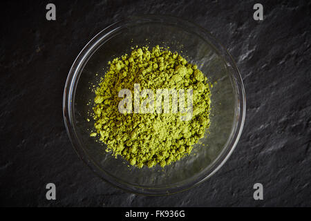 Matcha vert en poudre dans un bol en verre sur la plaque en pierre noire Banque D'Images