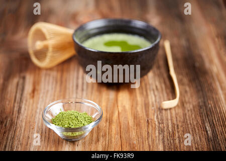 Thé matcha vert et en poudre, mélanger et verser sur une table en bois Banque D'Images