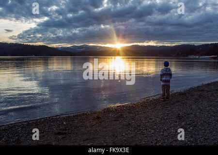 Montres garçon coucher de soleil sur le lac. Banque D'Images