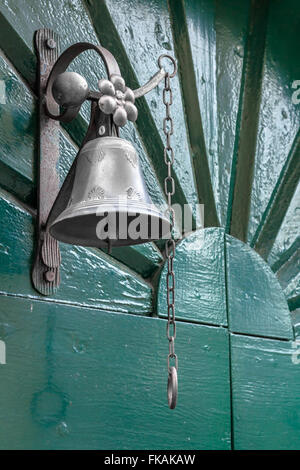 Bell en tant qu'ancienne porte sur porte en bois vert. Banque D'Images