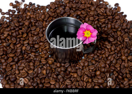 Tasse de café en acier dans les grains de café et une fleur Banque D'Images