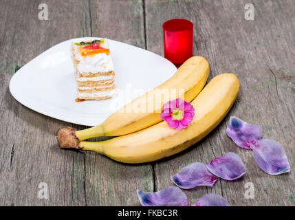 Deux bananes, plaque avec gâteau décoré de fleurs Banque D'Images